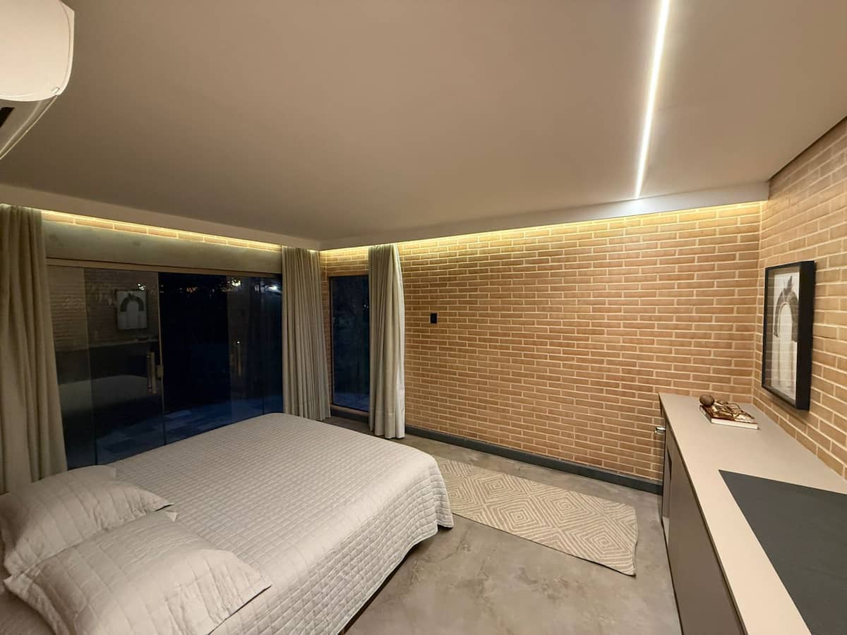 Quarto da Oka do Caju com cama king e parede de tijolo aparente